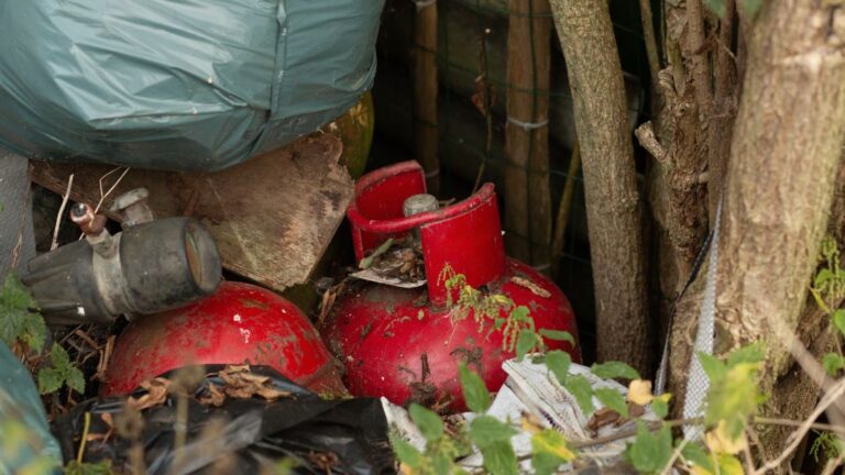 Image for How to Dispose of Old Gas Safe Disposal Guide for Industrial Facilities, showing two old, red propane tanks abandoned in brush and debris.