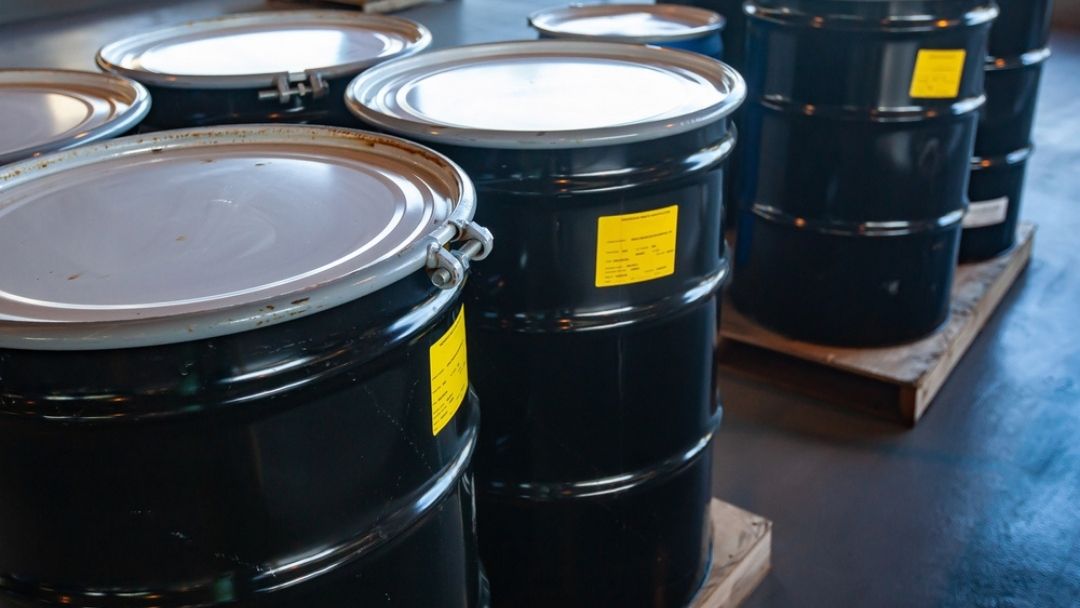 Industrial hazardous waste drums with safety labels showing storage and disposal strategies for reducing costs and improving efficiency