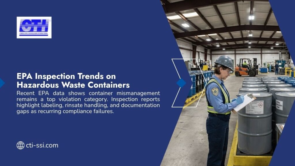 Female inspector in hard hat and safety vest reviewing clipboard next to rows of gray hazardous waste drums in industrial warehouse, with forklift visible in background.